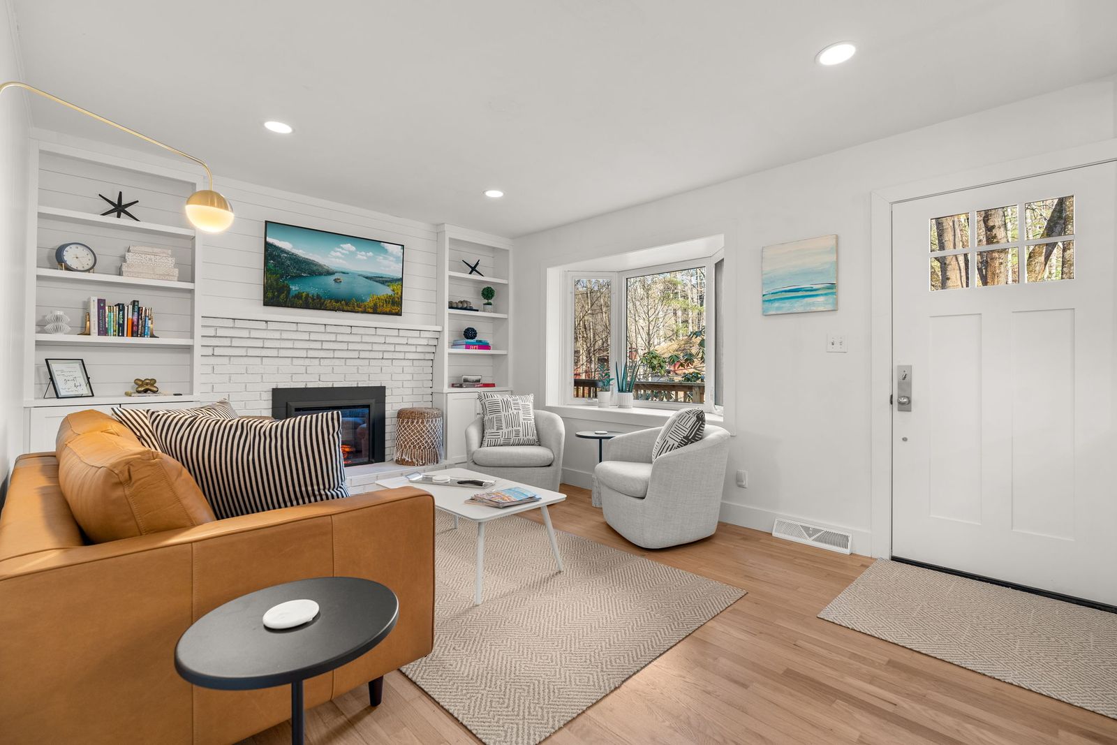 Living room with a fireplace, built-in shelving, and a bay window.